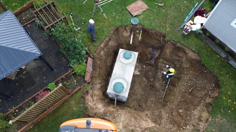 Aerial view of a new septic tank set in an excavation beside a home